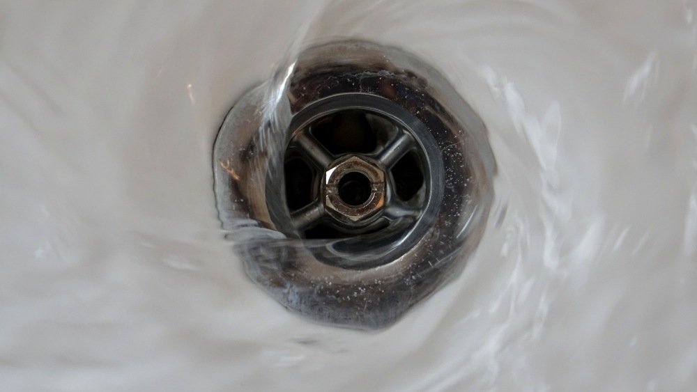 A close-up view of water draining into a kitchen sink, showcasing professional drain cleaning services in LA County.