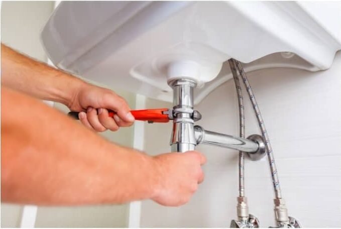 LA residential Plumber fixing a sink drain with a wrench during residential plumbing service in Los Angeles County.