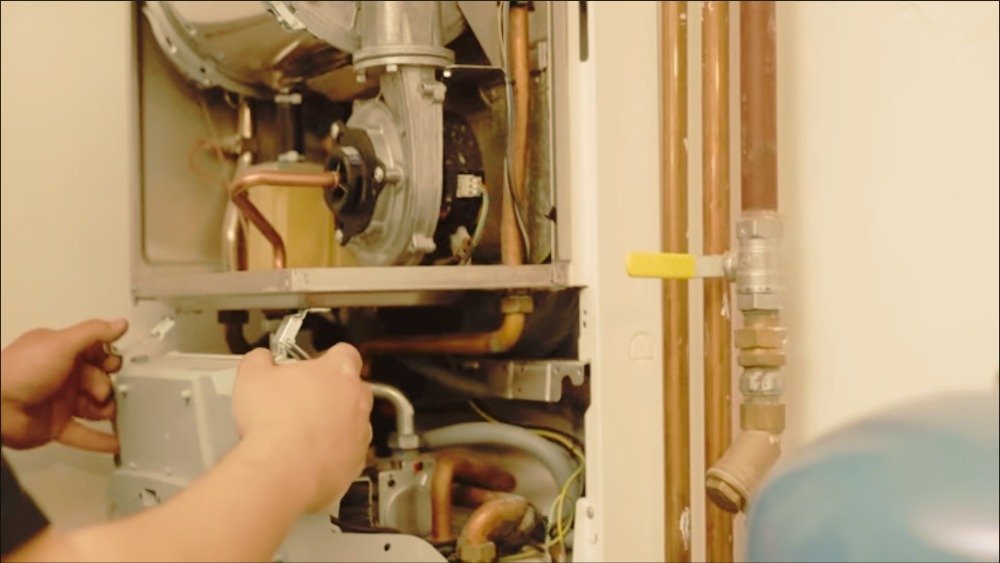 ATC Plumbing technician fixes a water heater on an open unit with visible internal components in Los Angeles, CA.