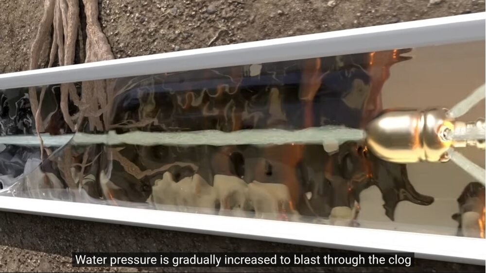 A drain hydro jetting nozzle blasting through a heavily clogged drain, clearing tree roots and debris with high-pressure water in Los angeles County.