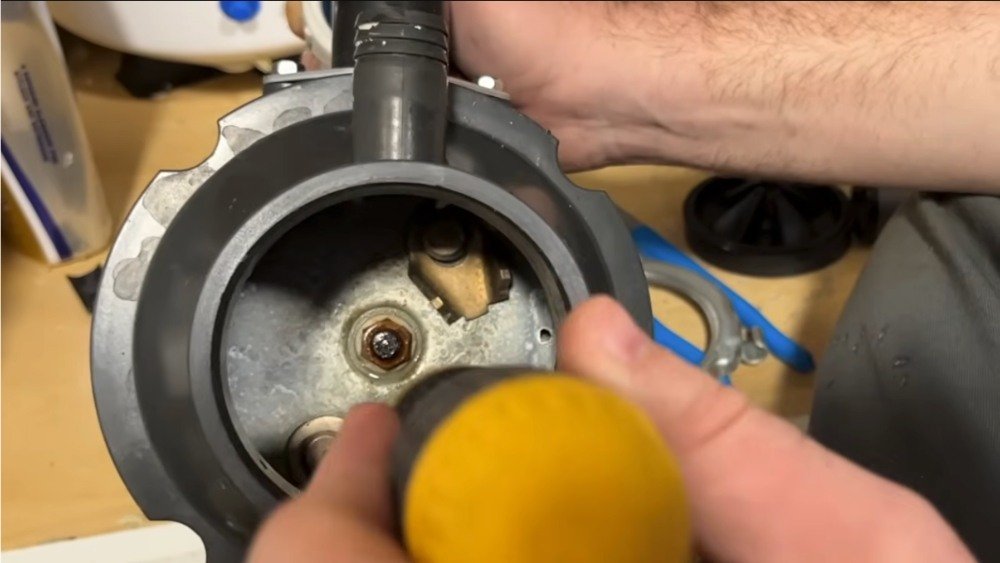 Close-up of a plumber using a screwdriver to repair the internal components of a jammed garbage disposal in LA.