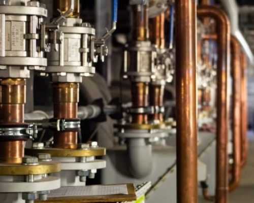 Complex commercial plumbing system with copper pipes and pressure control valves in Los Angeles County, CA.